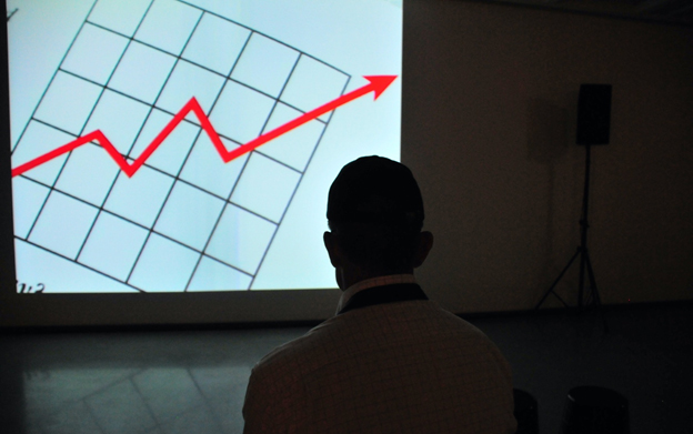 Man Looking at a Powerpoint Presentation of Numbers Going Upwards