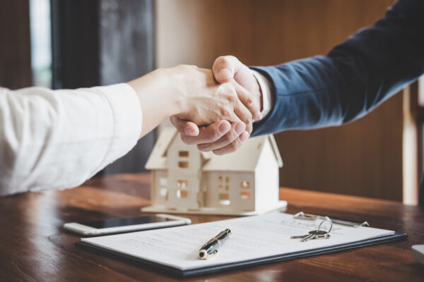 Real estate agent and customers shaking hands together celebrating a successful deal