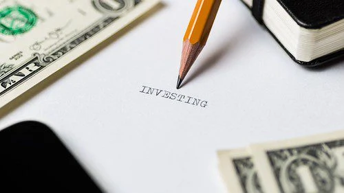 A pencil writing "investment" on a piece of paper