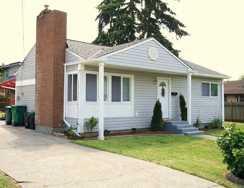 House with brick chimney and green trash cans