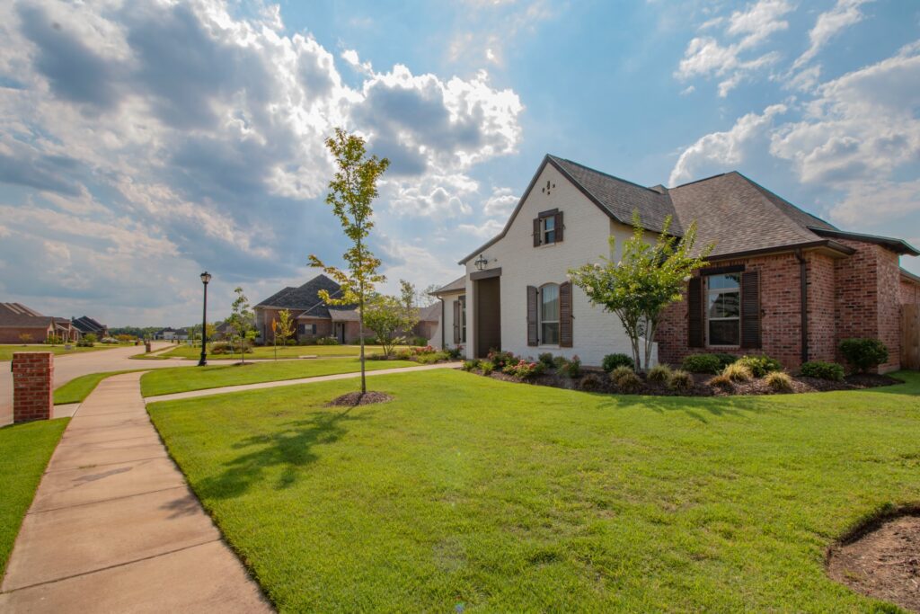 white and brown house near green grass field under white clouds