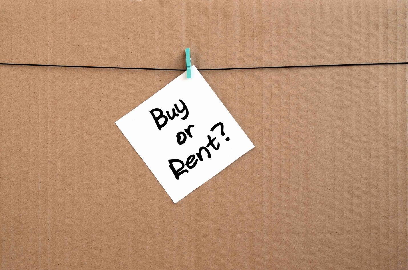 A sticky note that says "buy or rent?" on a cardboard box