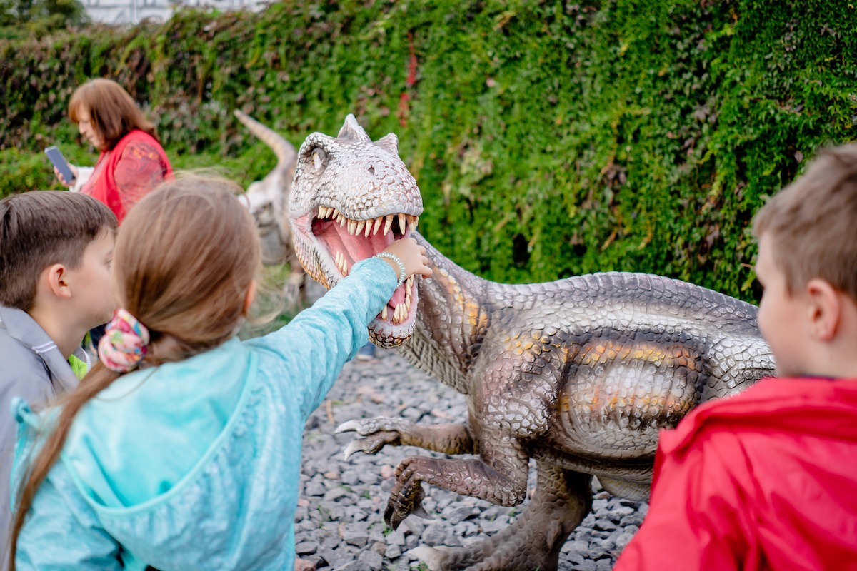 Children playing around fake dinosaurs at a science museum