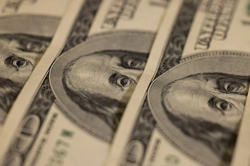 Up close photo of three hundred dollar bills laying vertically in a row
