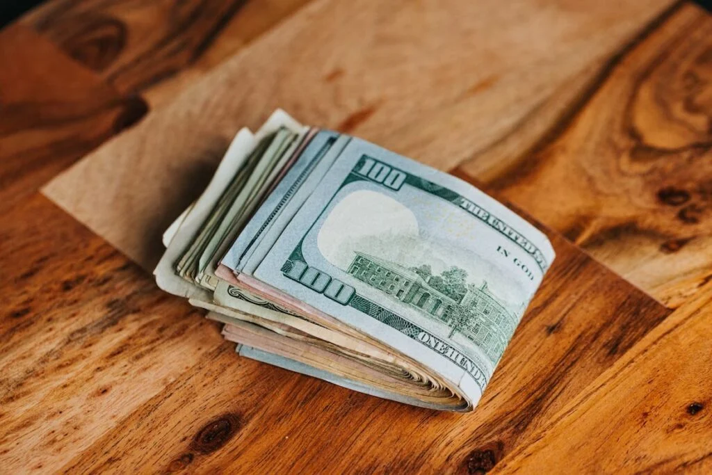 a pile of money laying on a wooden table