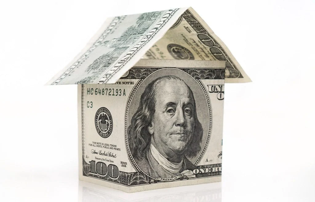 two money bills placed on a white background to look like the shape of a house