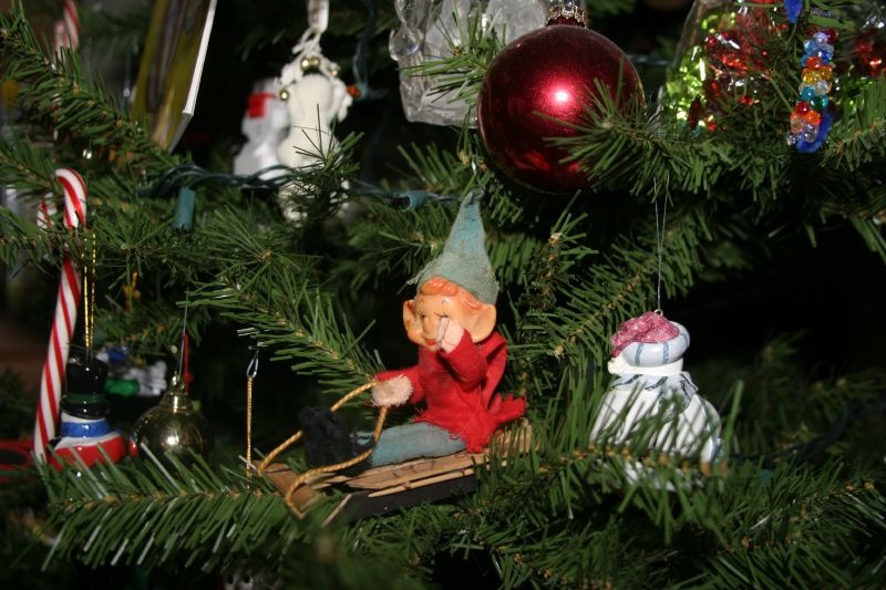 An elf sitting on the branches of a Christmas tree