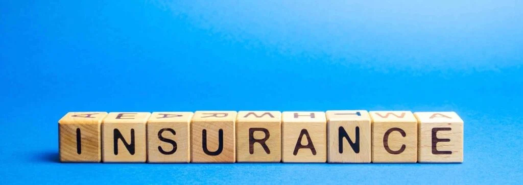 wooden letter blocks spelling out the word "insurance" with a blue background in the back