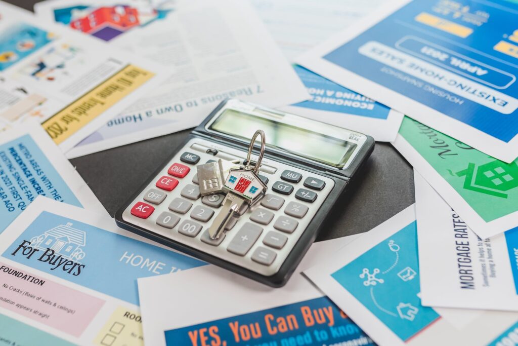 House keys sitting on a calculator with financial informational sheets in the background