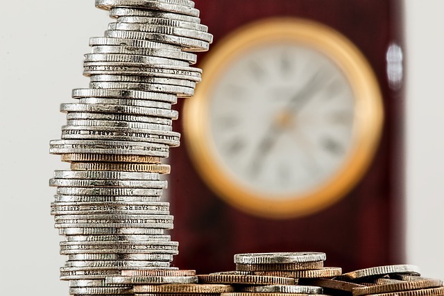 a stack of coins with an out of focus clock in the background