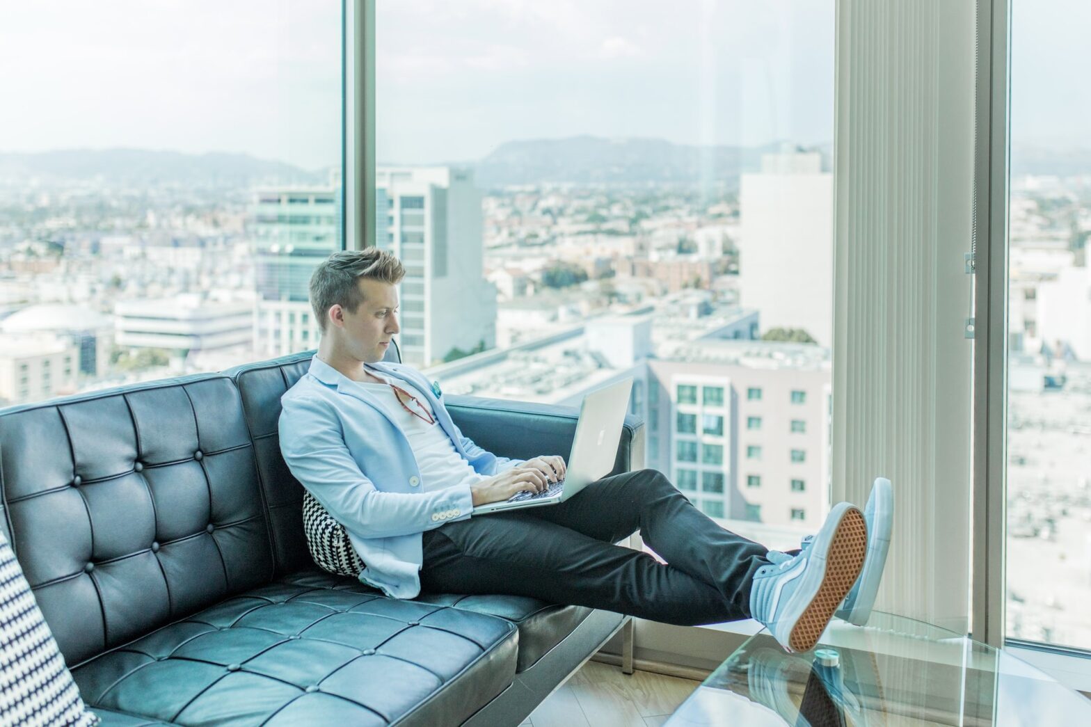 man sitting on a sofa with a laptop in a high rise apartment